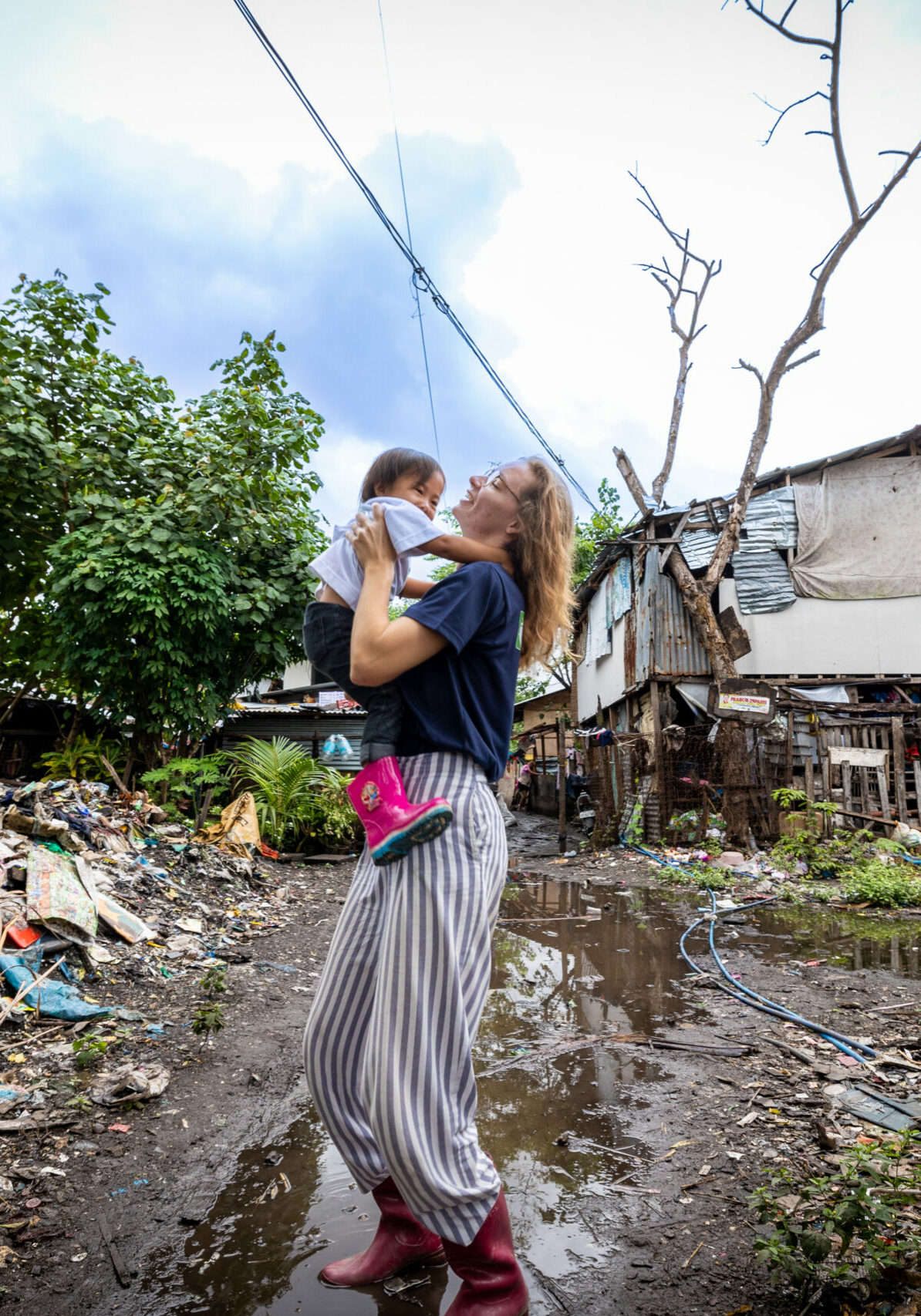 Audrey, volontaire bambou, porte une petite fille de la crèche d'Inayawan, une décharge de Cebu City aux Philippines